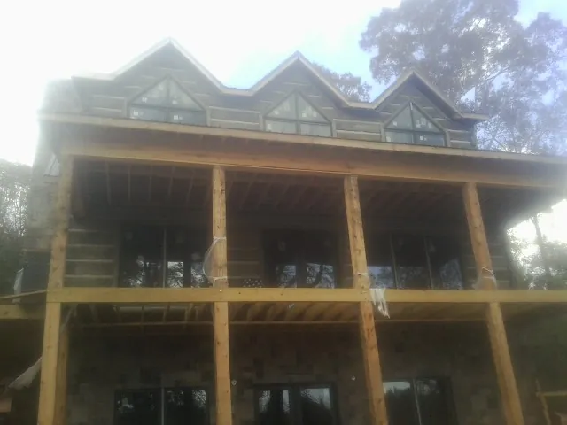 Dormers and porch framing on a large log home under construction — Roof Coating work by our crew in Melvern