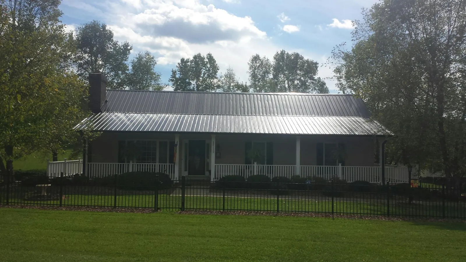 Gray metal roof on a brick ranch with a full width front porch — Gutter Guard Installation work by our crew in Melvern