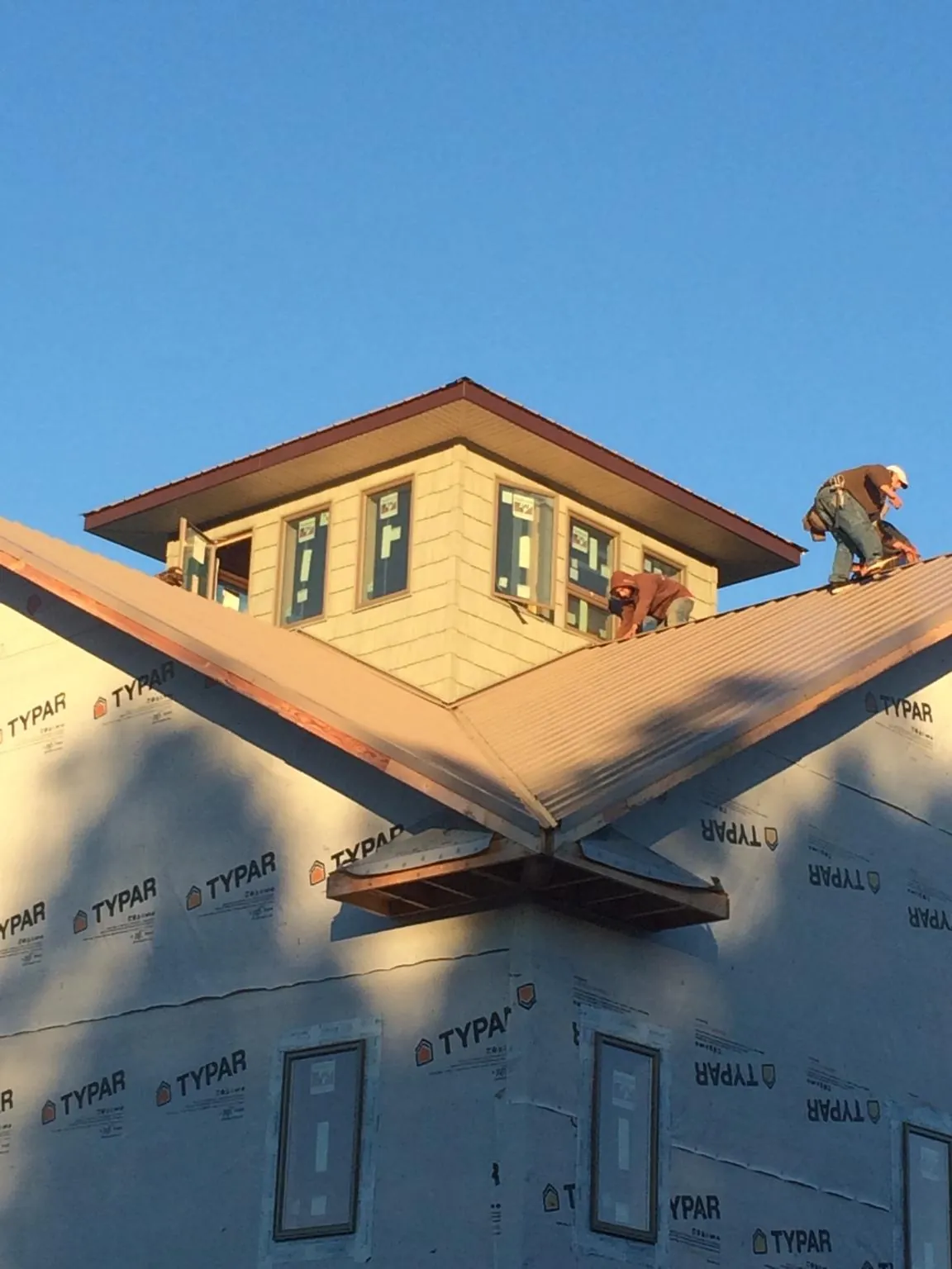 Roofers working around a rooftop cupola on a new metal roof at sunset — Roof Waterproofing in Melvern by Roofing Brothers